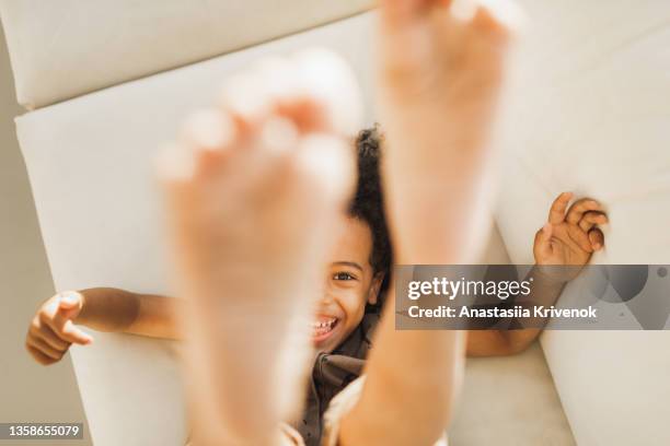 little black boy laughing and lifting legs to the camera. - feet model stock-fotos und bilder