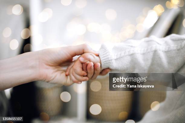 close-up of adult and baby toddler hands holding as a symbol of care, love and help - children charity fotografías e imágenes de stock