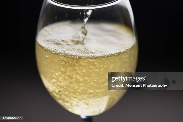 pouring in glass of white wine with ice with in bubbles - champagner gläser mit flasche unscharfer hintergrund stock-fotos und bilder