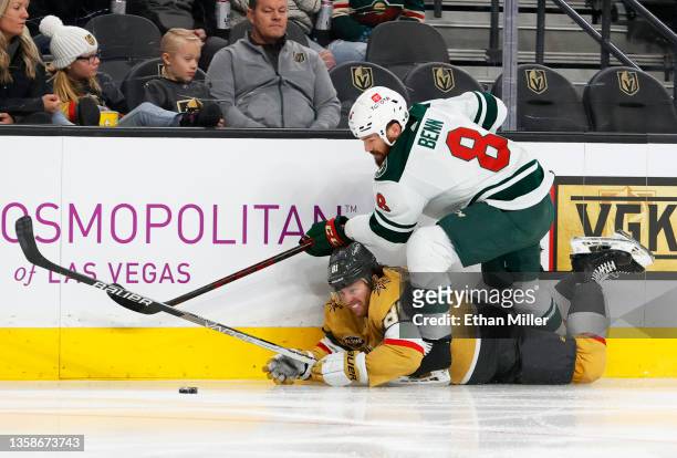 Jonathan Marchessault of the Vegas Golden Knights and Jordie Benn of the Minnesota Wild battle for the puck along the boards in the second period of...