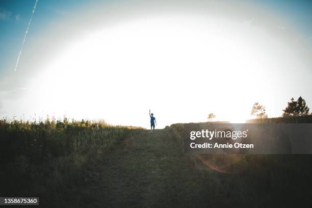 boy standing on top of a hill - prairie silhouette stock pictures, royalty-free photos & images