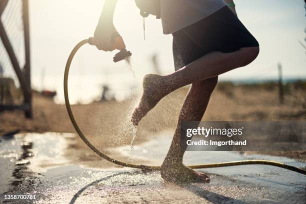 little boy washing sand off their feet - water wastage stock pictures, royalty-free photos & images