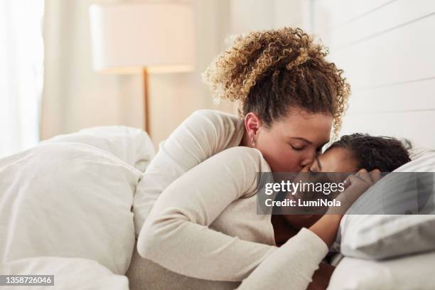 shot of a young lesbian couple lying in bed together and cuddling in the morning - asian lesbians kiss stock pictures, royalty-free photos & images