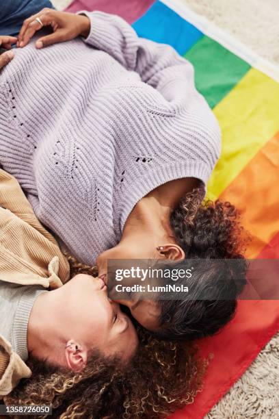 high angle shot of a young lesbian couple lying on a gay pride flag together and kissing - asian lesbians kiss stock pictures, royalty-free photos & images