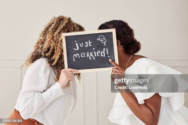shot of an unrecognisable lesbian couple standing together and kissing behind a just married sign after their wedding - asian lesbians kiss stock pictures, royalty-free photos & images