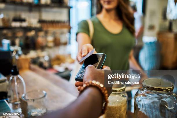 shot of a cashier helping a customer pay in a grocery store - consumerism imagens e fotografias de stock