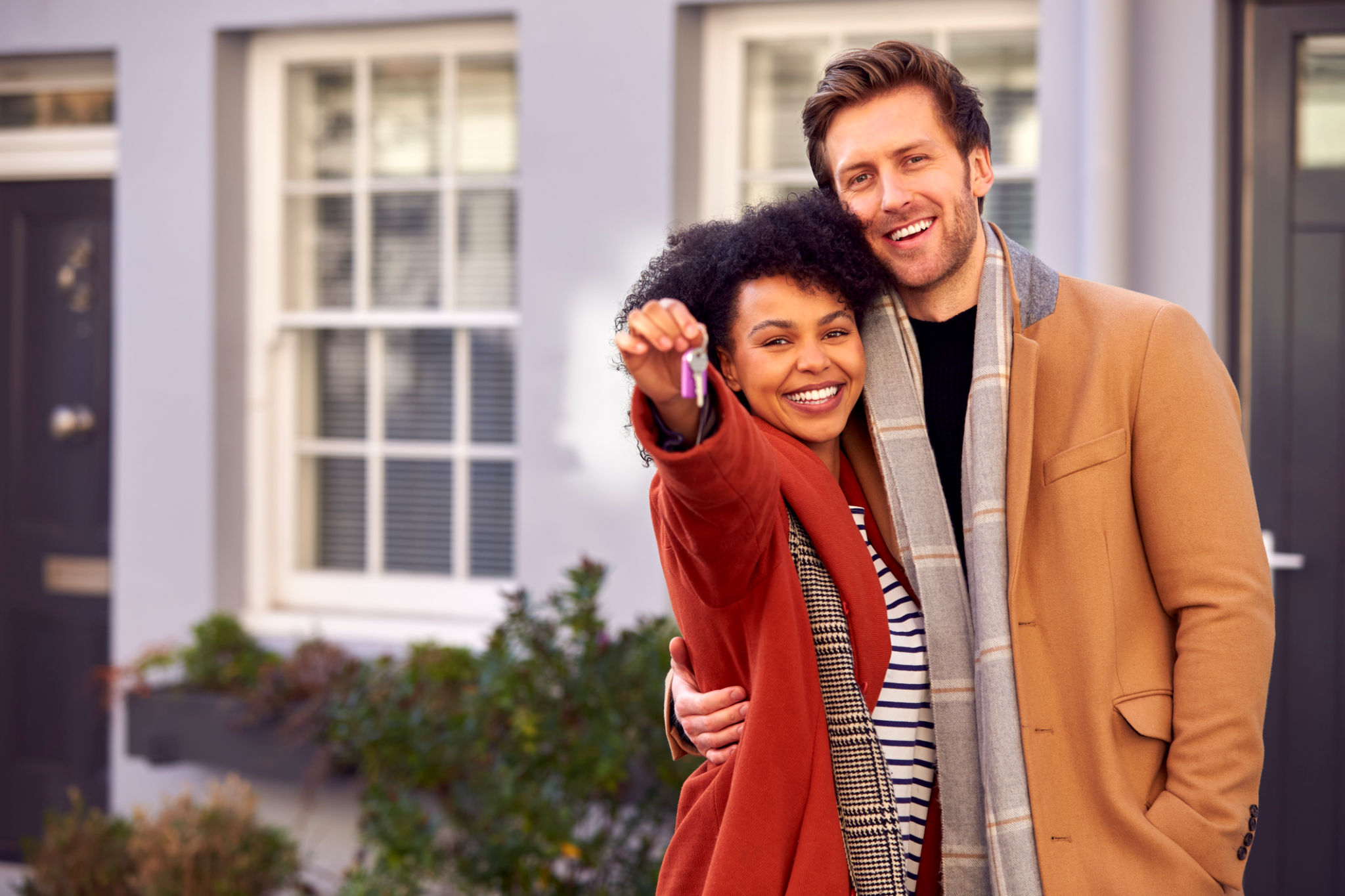 Portrait Of Multi Cultural Couple Outdoors On Moving Day Holding Keys To New Home In Fall Or Winter Portrait Of Multi Cultural Couple Outdoors On Moving Day Holding Keys To New Home In Fall Or Winter