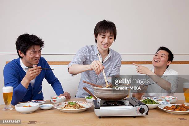 three men enjoying home party - hot pot dish fotografías e imágenes de stock