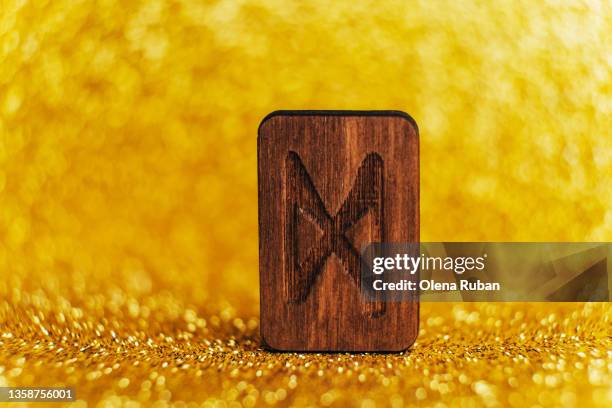 wooden rune dagaz on gold colored background. - numerology stock pictures, royalty-free photos & images