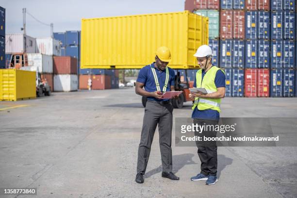 professional of two engineer container cargo foreman in helmets working standing and using walkie talkie checking stock into container for loading.logistic and business export - safe harbor stock pictures, royalty-free photos & images