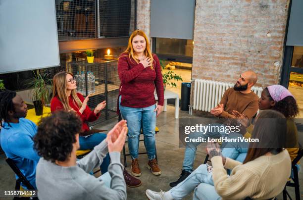 frau im gespräch mit den anderen mitgliedern der therapiegruppe - men and women in a large group listening stock-fotos und bilder