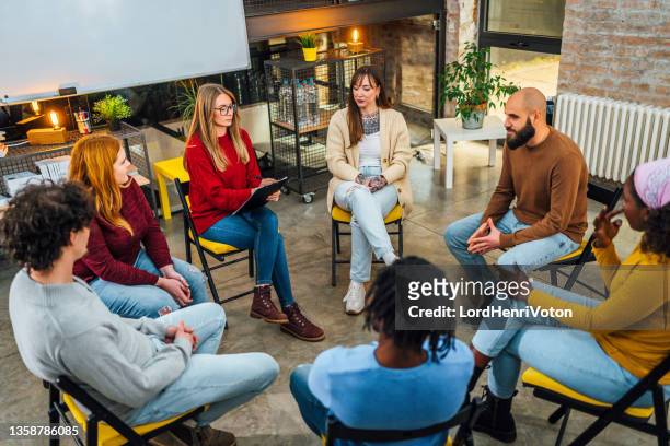 gruppe von menschen, die in einem kreis auf gruppentherapie sitzen - storytelling recomendation stock-fotos und bilder