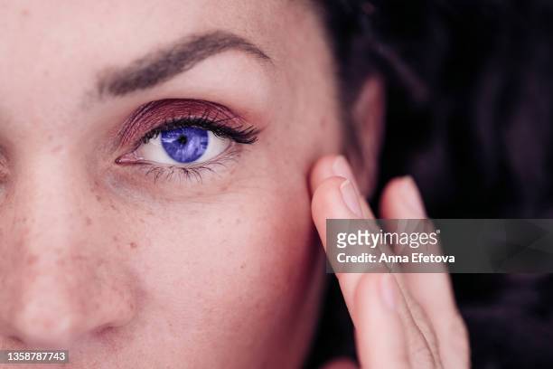 close-up of beautiful female purple eye with light daily makeup and fingers touching perfect skin. concept of natural beauty. demonstrating very peri, color of 2022 year. - beauty salon ukraine - fotografias e filmes do acervo