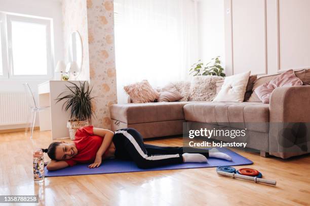 joven feliz descansando en una colchoneta de ejercicios después de hacer ejercicio en casa - acostado de lado fotografías e imágenes de stock