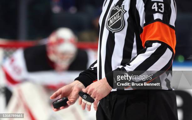 Referee prepares to drop the puck for the game between the New York Islanders and the New Jersey Devils at the UBS Arena on December 11, 2021 in...
