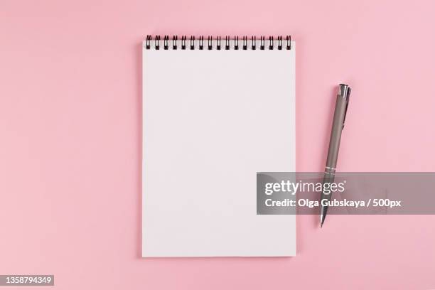 notebook with blank page and a ballpoint pen lie on pink background - folder mockup stockfoto's en -beelden