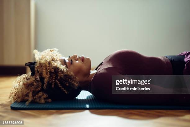 relaxation: beautiful afro-american woman doing yoga - woman lying down stock pictures, royalty-free photos & images