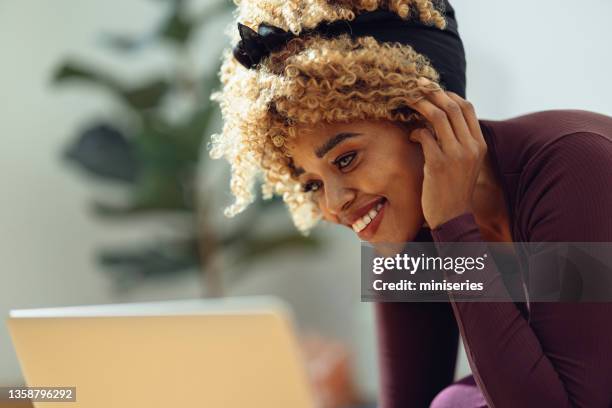 afroamerikanerin schaut auf ihren laptop - headband stock-fotos und bilder