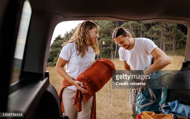young couple preparing gear for hike - bilsemester bildbanksfoton och bilder