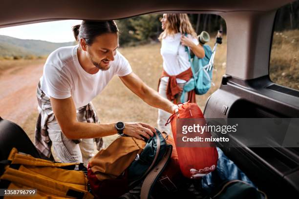 mann nimmt rucksack für wanderung aus dem kofferraum - holiday packing stock-fotos und bilder