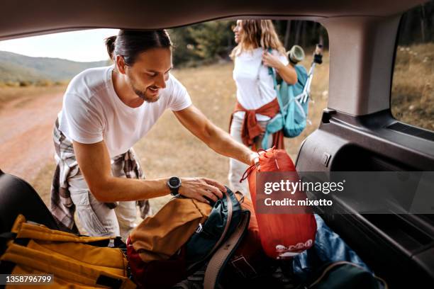 man taking backpack for hike from car trunk - holiday preparation stock pictures, royalty-free photos & images