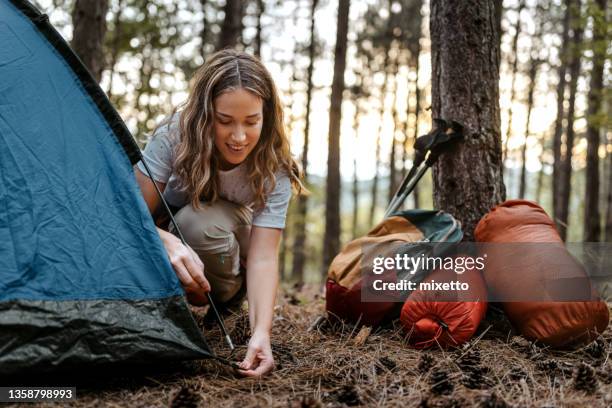 woman building tent in forest - beautiful woman camping stock pictures, royalty-free photos & images