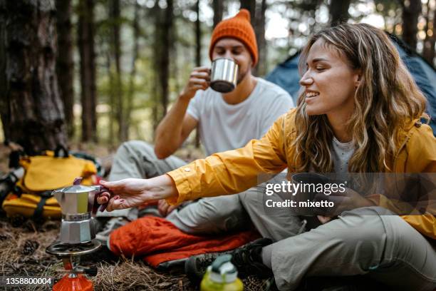 junges paar kocht kaffee beim wandern - sitting drinking coffee man stock-fotos und bilder