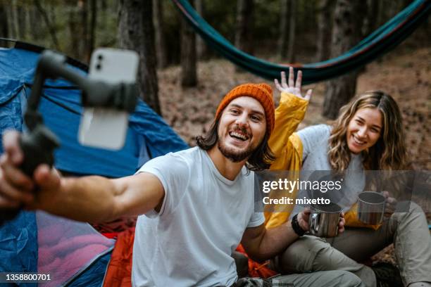 happy couple drinking coffee and using smart phone - happy couple using cellphone stockfoto's en -beelden