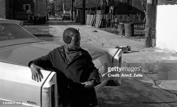 View of an young boy as he leans on a Cadillac DeVille parked in the empty lot, in the Lawndale neighborhood, Chicago, Illinois, September or October...