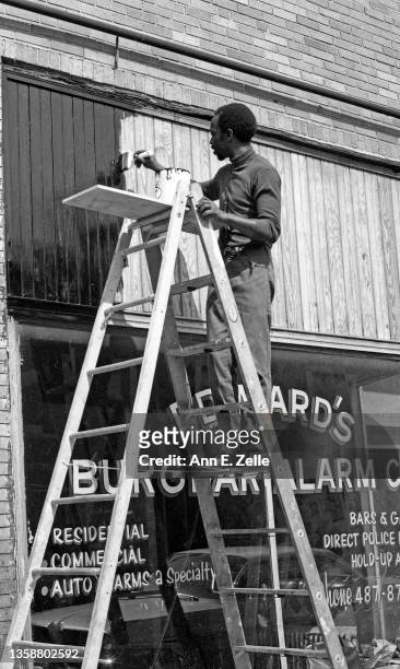 American artist and Art & Soul Director Jackie Hetherington stands on a ladder as he paints the exterior of a storefront on West 16th Street, in the...