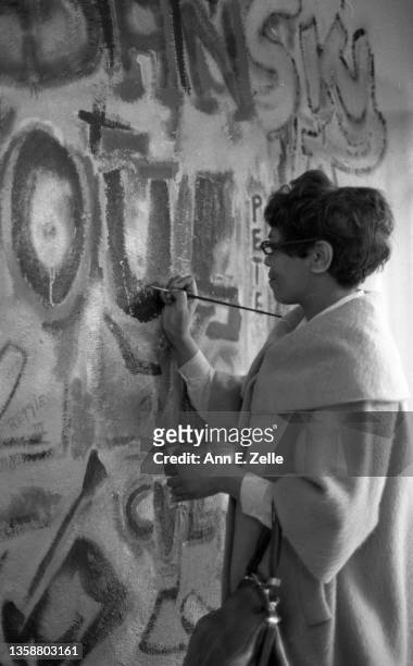 An unidentified woman paints her name on a wall as she attends the opening event for the Art Contest Exhibition at the Art & Soul community art...