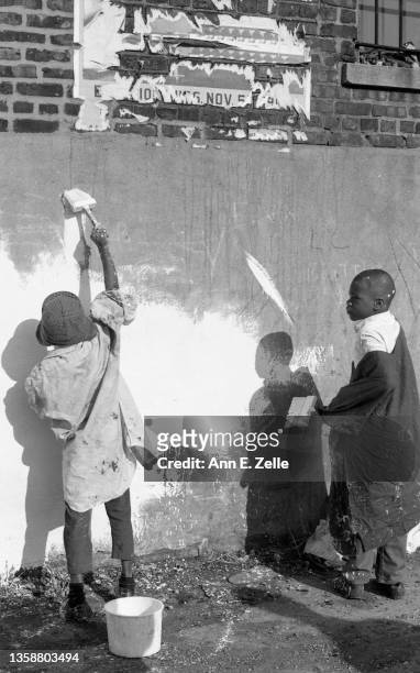 View of a pair of unidentified boys as they help to whitewash the side wall of the Art & Soul community art center , in the Lawndale neighborhood,...