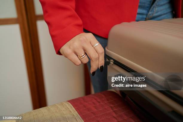 closeup of a woman unzipping her suitcase on a hotel bed - handle stock-fotos und bilder
