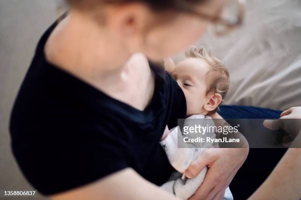 mother breastfeeding baby at home - dia bildbanksfoton och bilder