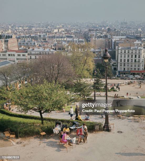 View from in front of Sacre-Coeur Basilica of residents and visitors walking down steps in Square Louise-Michel in the 18th arrondissement of Paris,...