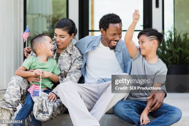 sitting on front stoop military family waves small american flags - army wife stock pictures, royalty-free photos & images