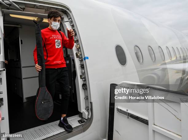 Mask-clad young member of ANIM group carries his musical instrument and Afghan passport as he exits the SAS charter flight that brought Afghanistan...