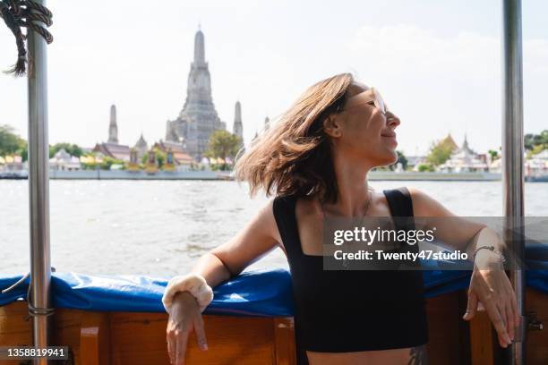 caucasian woman discover bangkok riding a boat in chao phraya river looking out from the boat - thailand boat ストックフォトと画像