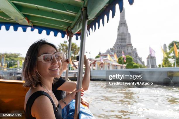 two caucasian women discover bangkok riding a boat in chao phraya river looking out from the boat - camera boat stock pictures, royalty-free photos & images