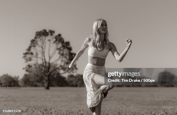 country dance,portrait of woman jumping on field against sky - drake one dance stock-fotos und bilder