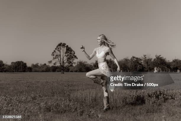 country dance,full length of woman jumping on field against clear sky - drake one dance stock-fotos und bilder