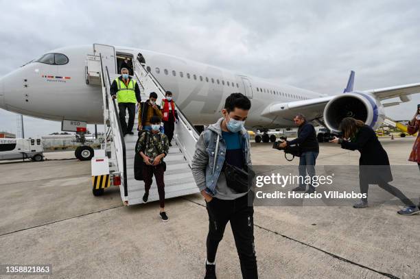 Mask-clad members of ANIM are being filmed as they exit the SAS charter flight that brought Afghanistan National Institute of Music 's 273 Students,...