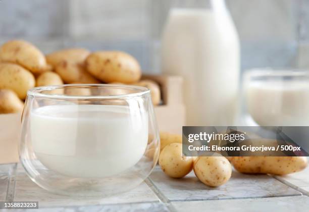 vegan potato milk in glass and potato on ceramic tile background - prepared potato stock pictures, royalty-free photos & images