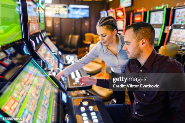 two friends gambling on slot machine at the casino - casino worker stockfoto's en -beelden