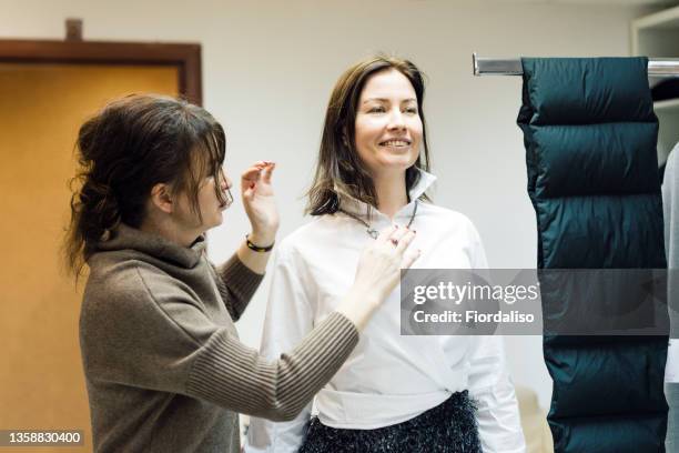 two middle-aged women pick up clothes in a boutique - modestylistin stock-fotos und bilder