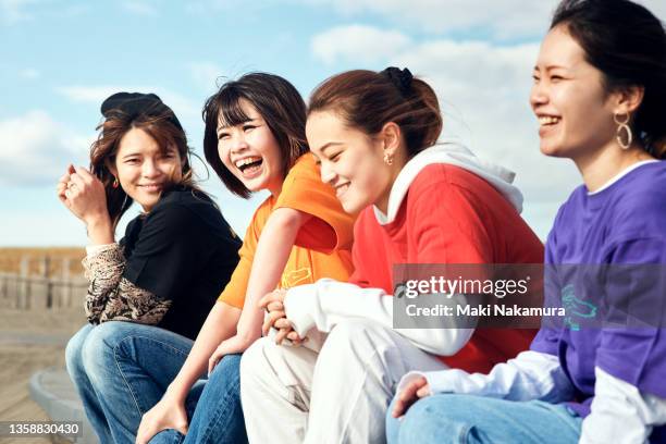 young women talking with a smile under the blue sky. - group women smiling stock-fotos und bilder