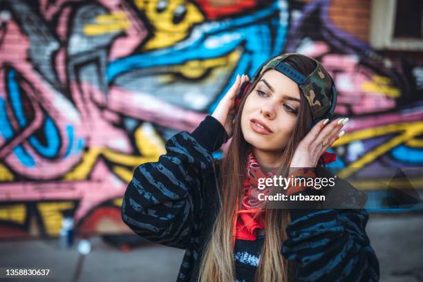 young urban woman listening to music - fashion pretty woman listening music in headphones with smartphone colorful stockfoto's en -beelden