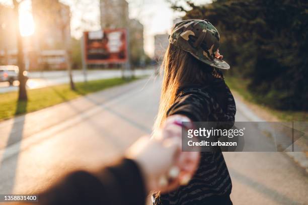 una mujer urbana sosteniendo la mano de su novio - seguir actividad móvil general fotografías e imágenes de stock