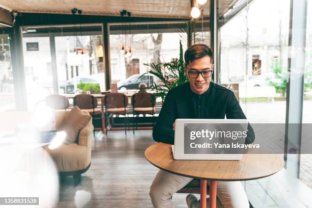 young asian entrepreneur trading with laptop in public place - laptop remote location stock pictures, royalty-free photos & images