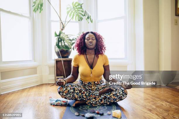 relaxed young woman meditating on yoga mat - showus yoga stock pictures, royalty-free photos & images